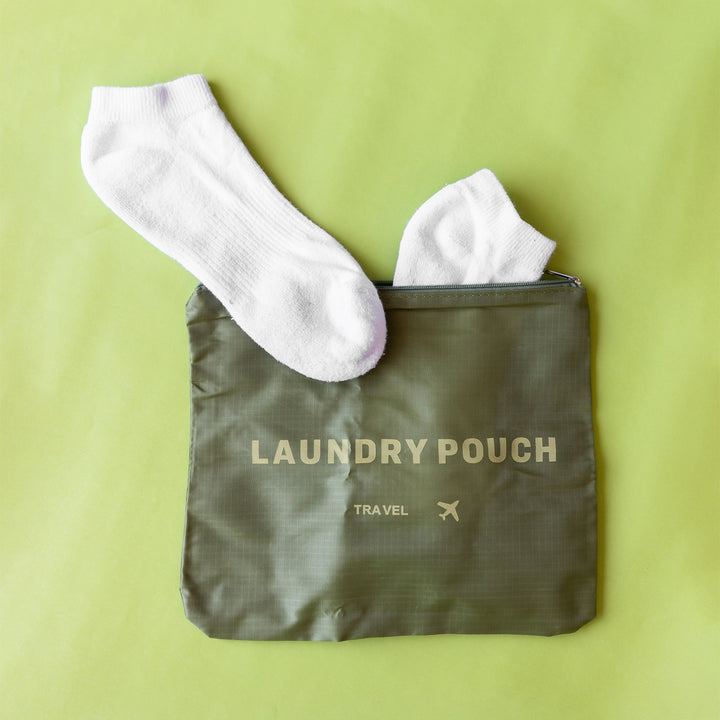 a pair of socks sticking out of a green laundry pouch.