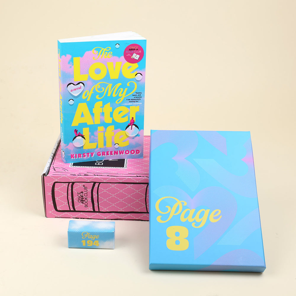 The Magical Realism Mini box items featuring the book 'Love of my Afterlife' by Kristy Greenwood, a blue wrapped gift labeled 'PAGE 8', and a small blue and white gift with text reading 'PAGE 194', arranged on a beige background.