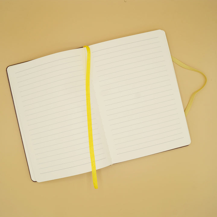 a journal with lined paper lays open with a yellow bookmark over the center