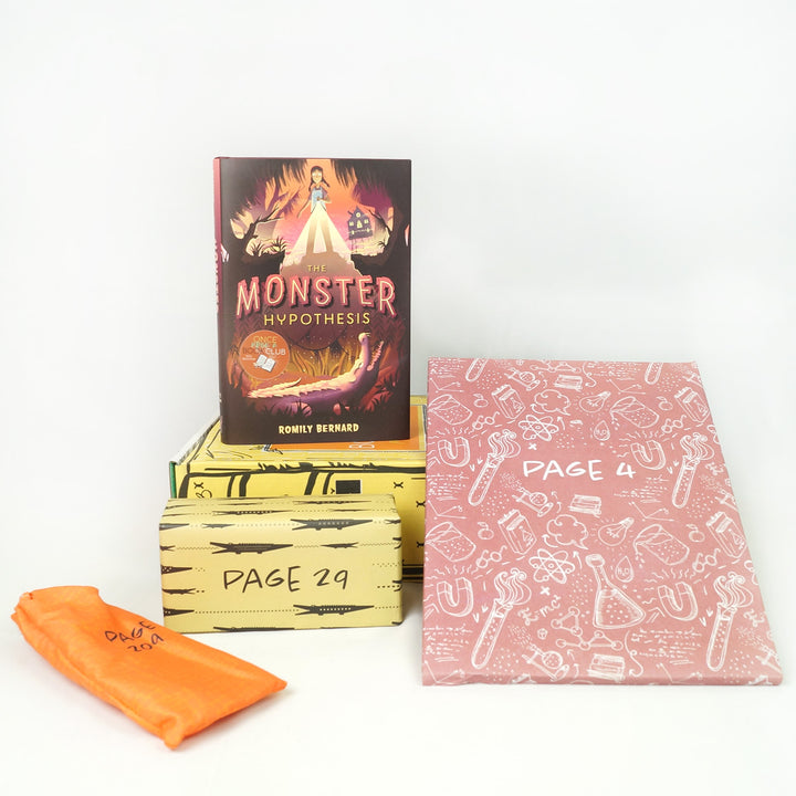 A hardcover edition of The Monster Hypothesis is on top of a yellow Once Upon a Book Club box. In front of the box are a yellow rectangular box, an orange drawstring bag, and folder. The boxes and bags all have page numbers.
