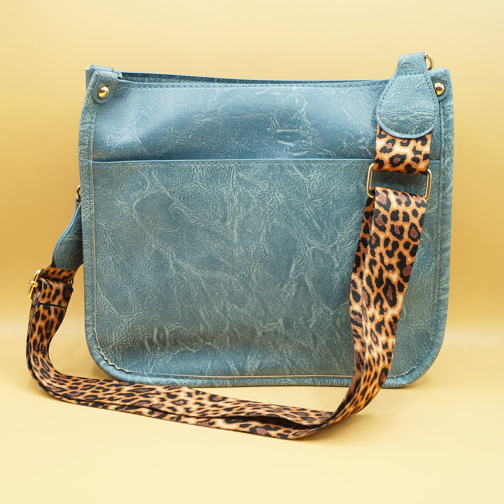 a blue faux leather bag with leopard print strap 