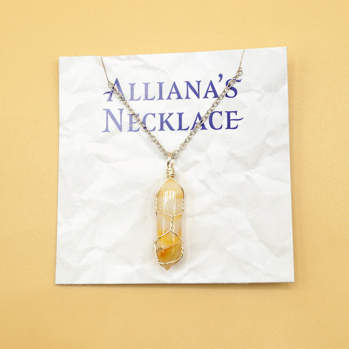 A yellow and clear crystal wrapped in silver wire on a silver chain. On a card that reads "Alliana's necklace".
