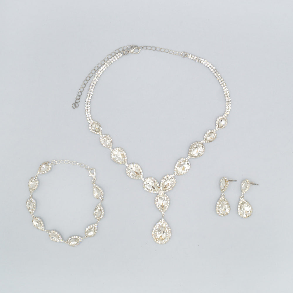 On a white background lays a pair of CZ drop earrings, CZ teardrop pendant necklace, and CZ teardrop bracelet.
