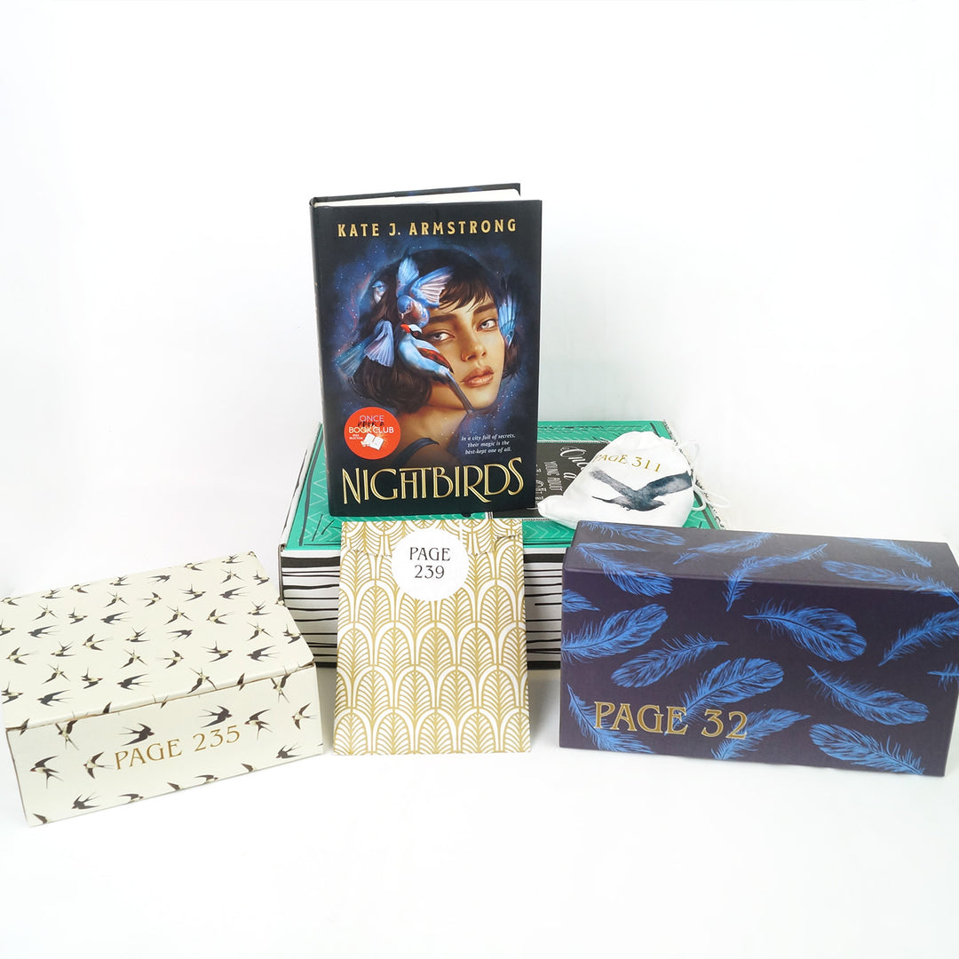 A hardcover edition of Nightbirds and a white drawstring bag are on a green Once Upon a Book Club box. In front of the box are a white box, gold and white envelope, and blue and black rectangular box. The boxes and envelope all have page numbers.