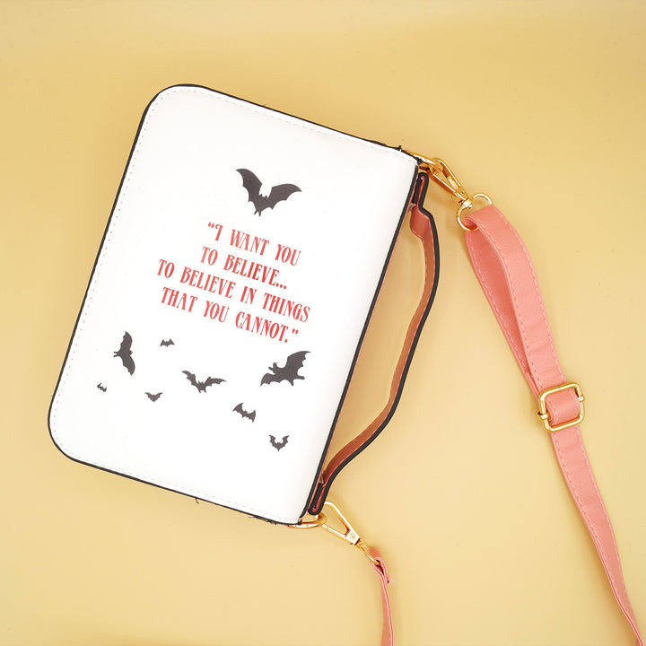 the back of a white purse with a pink strap. there are images of black bats on it and the quote "I want you to believe...to believe in things that you cannot"
