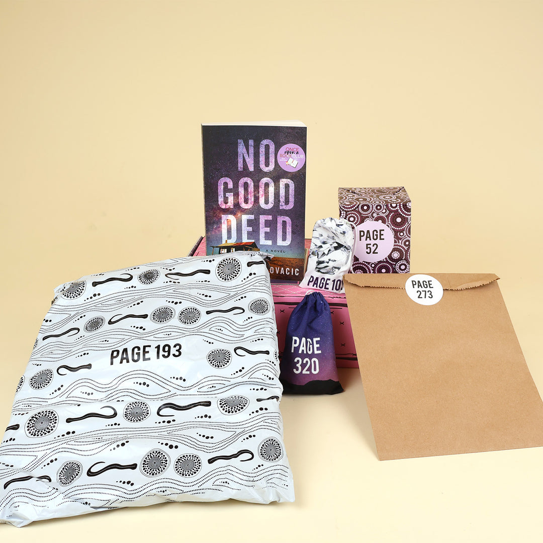 A paperback edition of No Good Deed stands on a pink OUABC box next to two themed wrapped gifts labeled with page numbers. In front of the pink OUABC box are three more themed wrapped gifts labeled with page numbers.