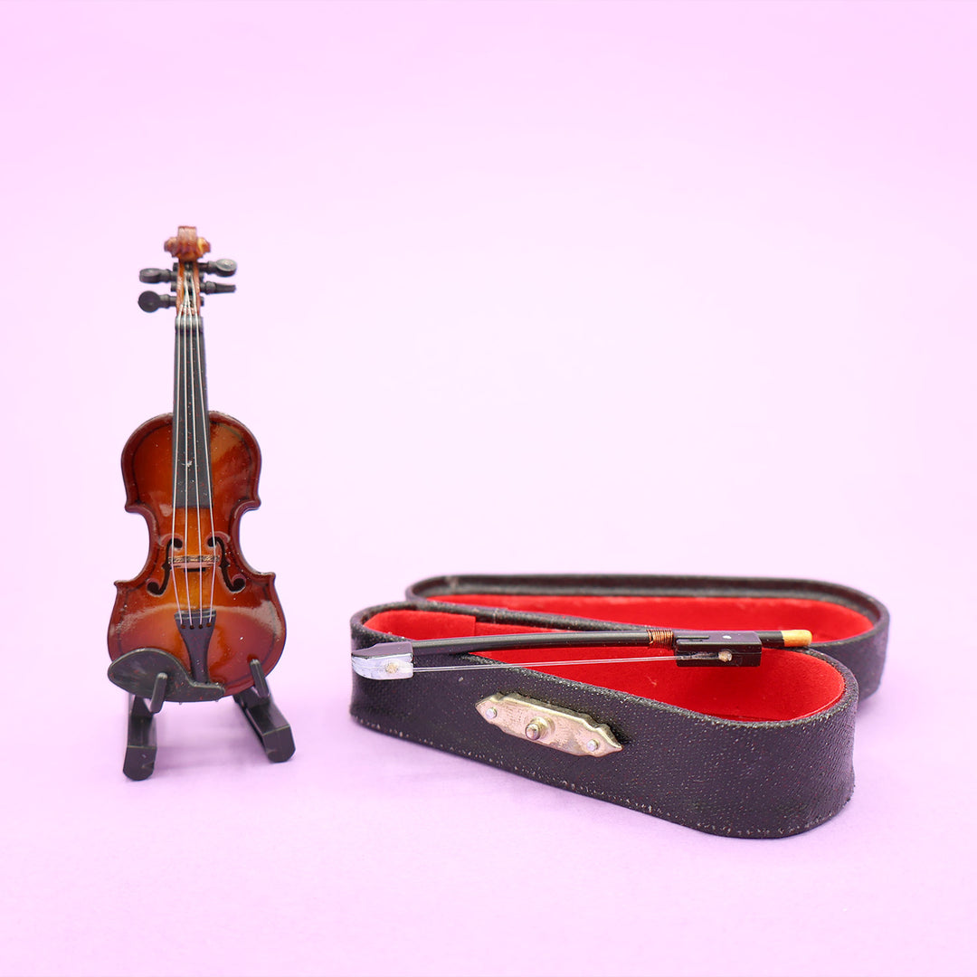 An open mini violin case next to a mini replica of a violin