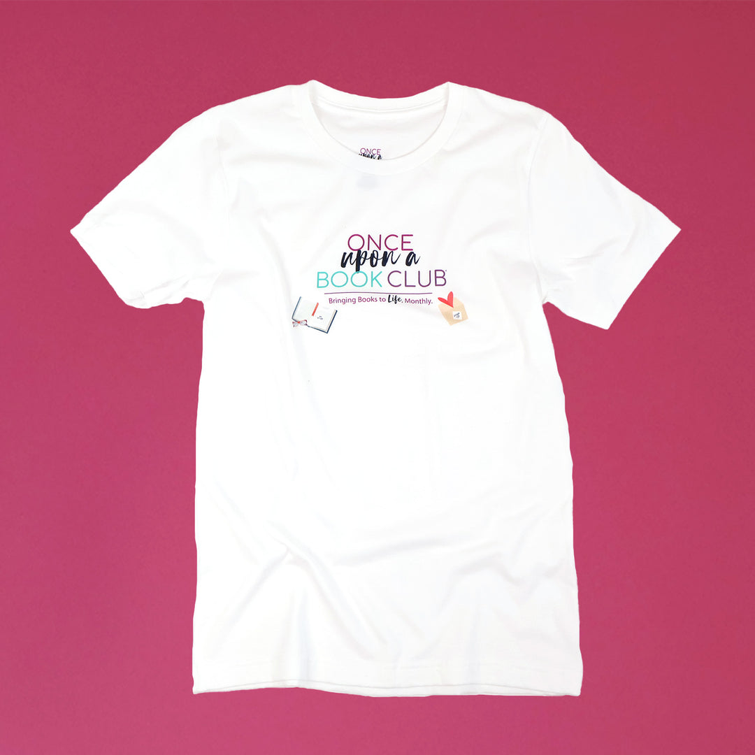 A white short-sleeve crewneck t-shirt with a colorful graphic on the chest reading 'Once Upon a Book Club' and 'Bringing Books to Life Monthly', laid flat against a solid magenta-pink background.