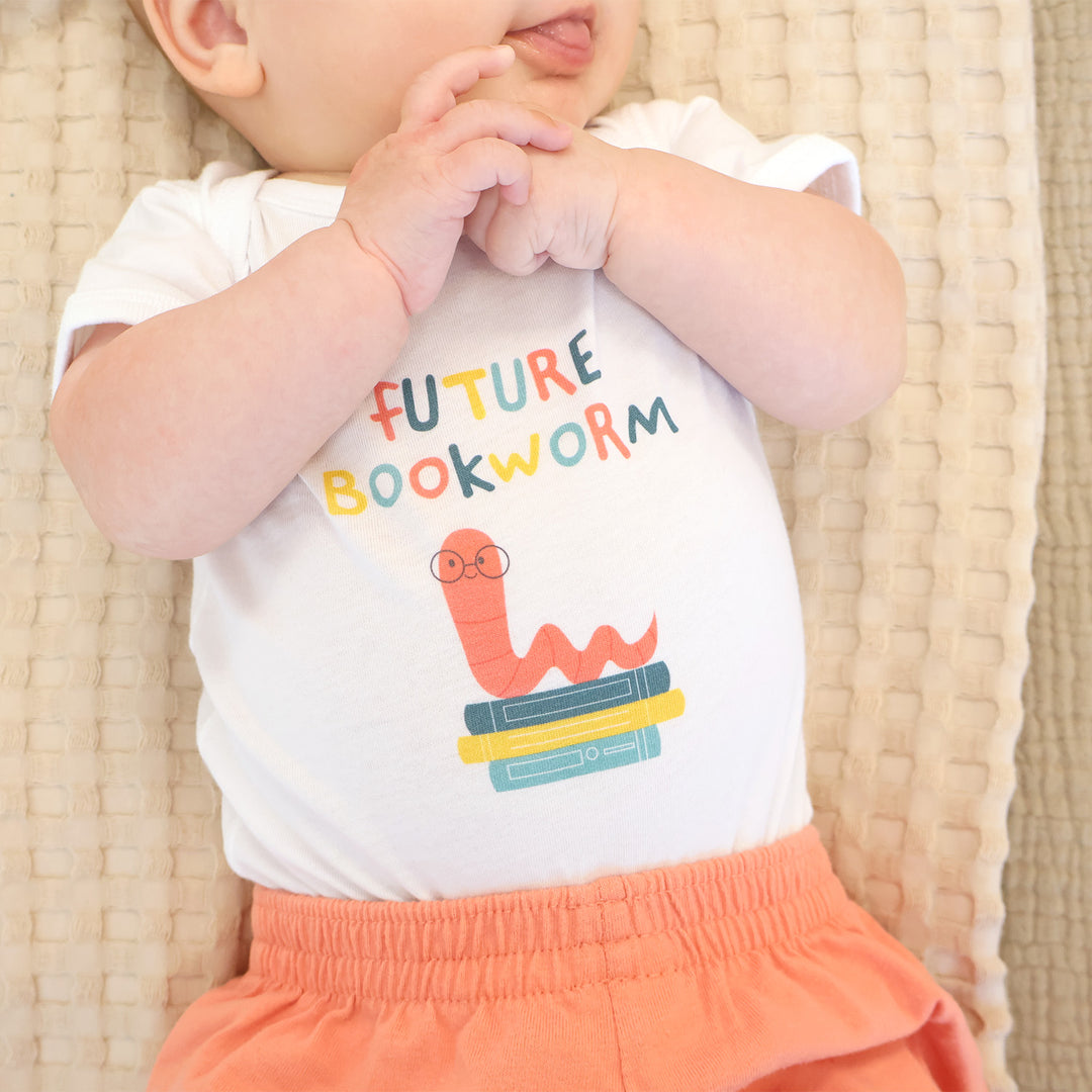 Baby wearing a onesie with 'Future Bookworm' text and graphic on a woven surface