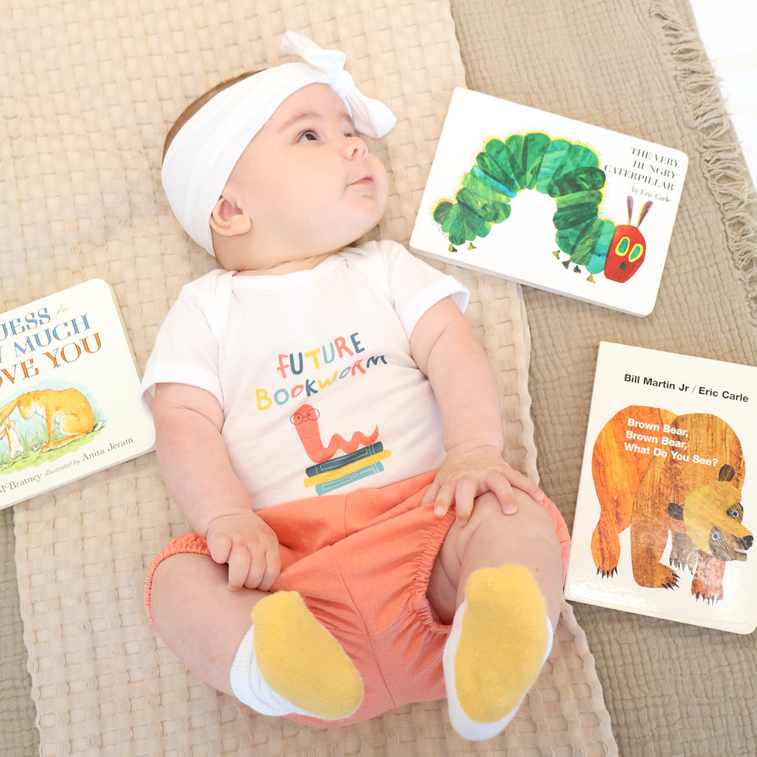Baby wearing a 'Future Bookworm' shirt with children's books around