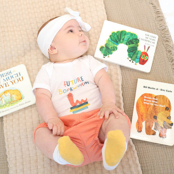 Baby wearing a 'Future Bookworm' shirt with children's books around