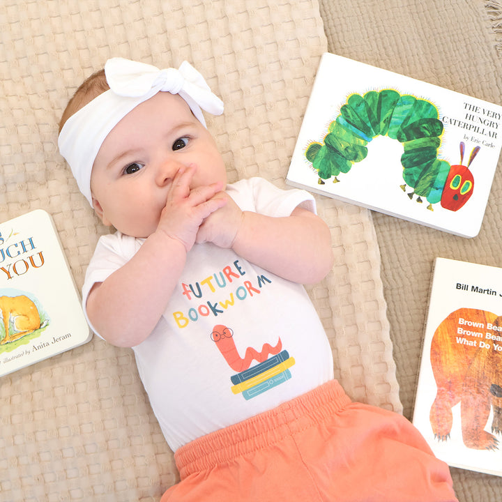 Baby wearing a 'Future Bookworm' onesie with children's books around