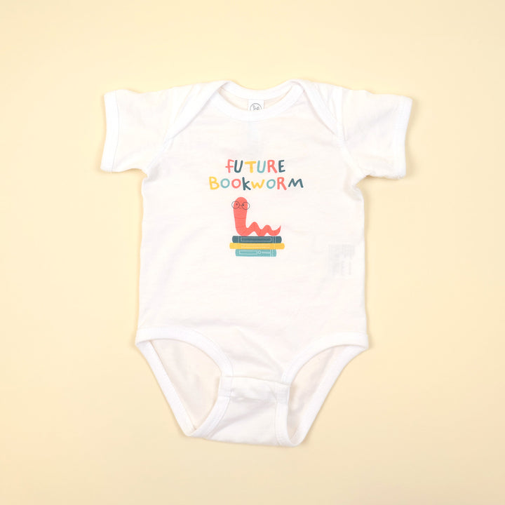White baby onesie with 'Future Bookworm' text and worm wearing glasses on a stack of books on a beige background