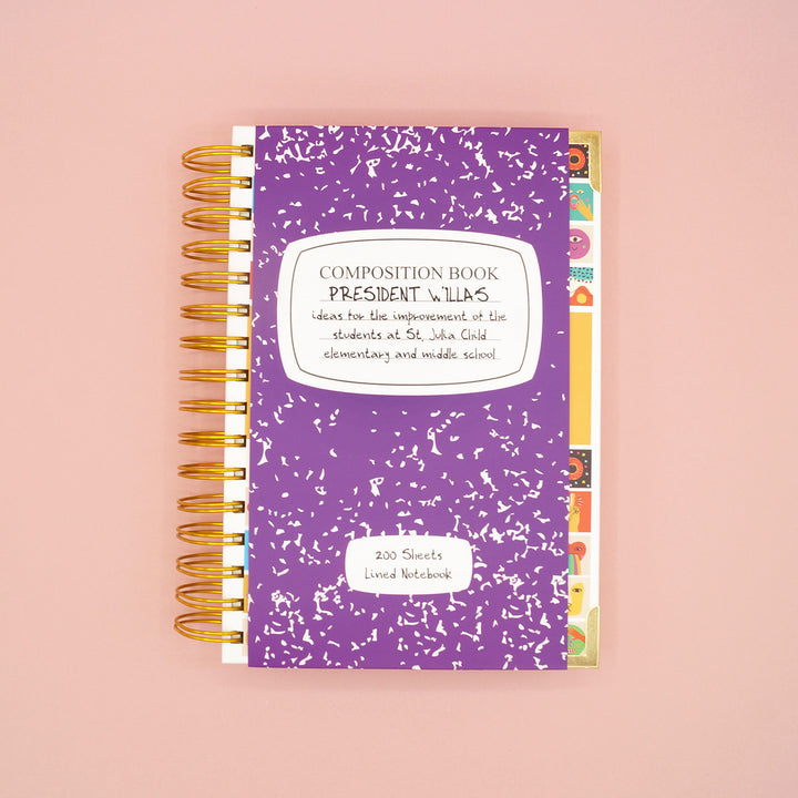 A purple paper wrap that is around the front cover of the ringed lined notebook upon receiving. The wrap is inspired by the description in the book, The League of Picky Eaters by Stephanie V.W. Lucianovic.