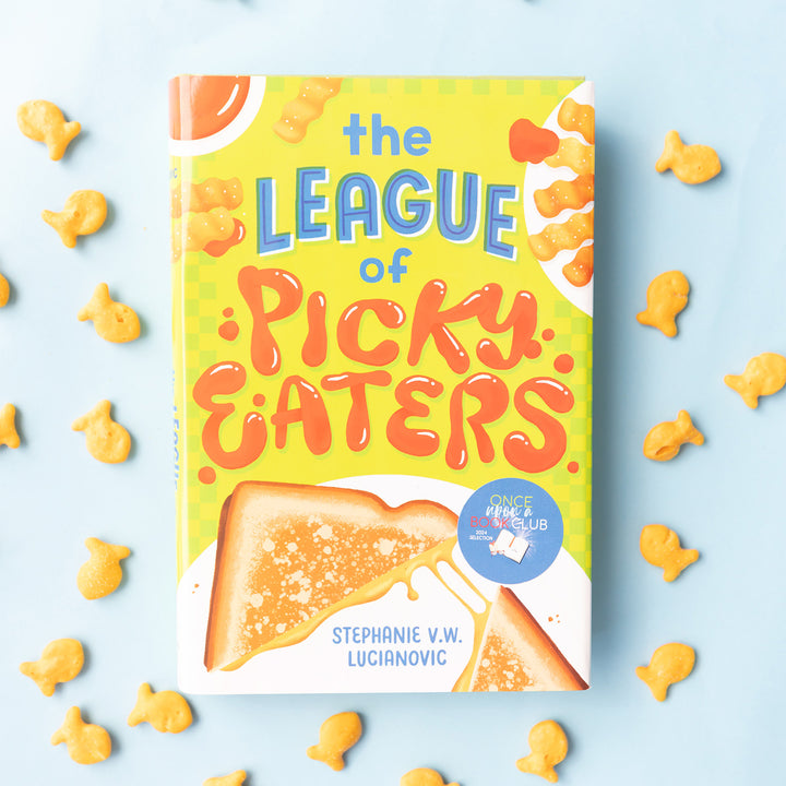 A hardcover copy of The League of Picky Eaters by Stephanie V.W. Lucianovic surrounded by Goldfish crackers.