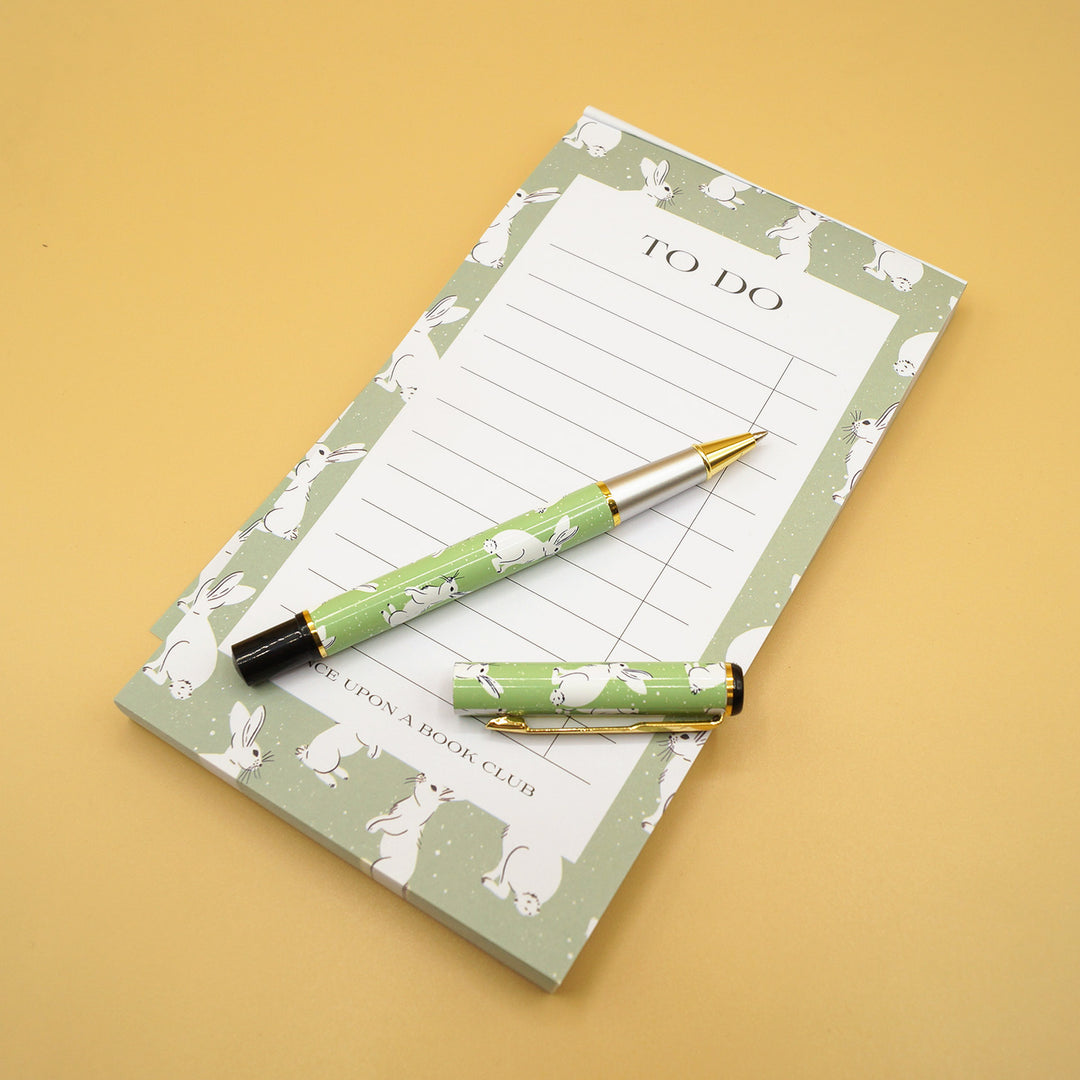 The notepad sits on a yellow background. The pen is now open to show that the cap comes off.