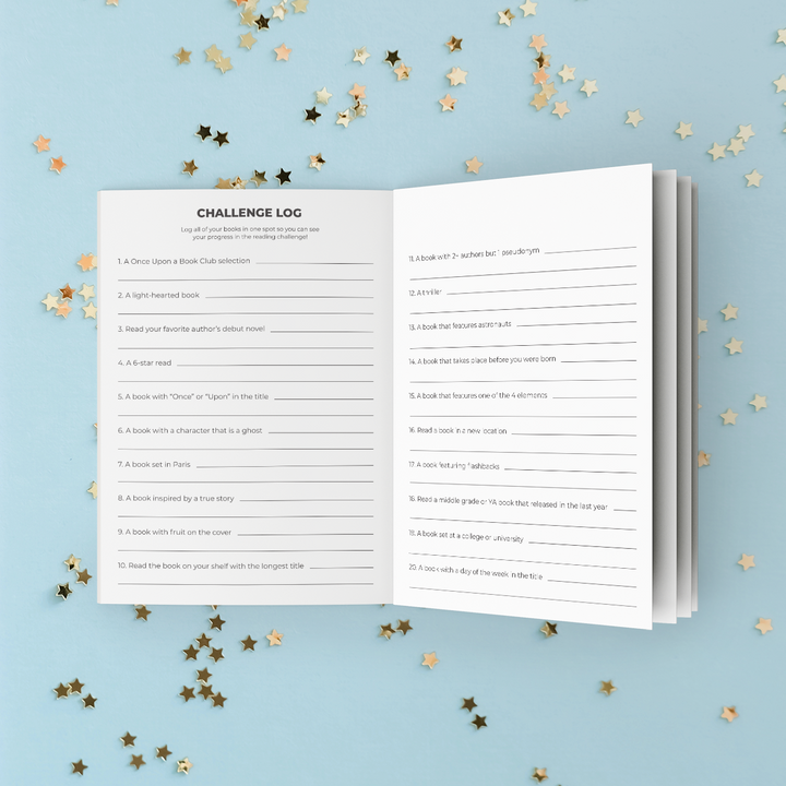 An open sneak peek of the Reading Challenge booklet index with lined writing areas and prompts, photographed on a light blue background with scattered gold star confetti.
