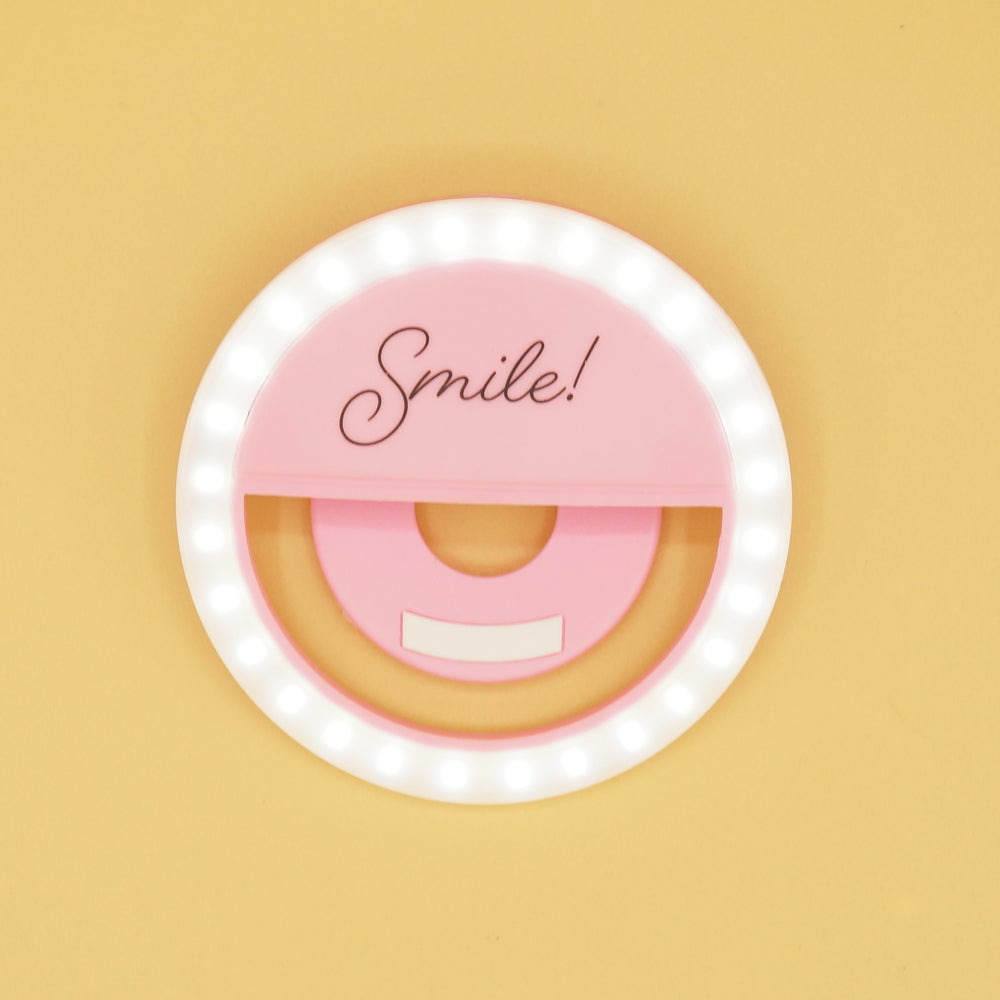 A light pink ring light that says Smile! on it