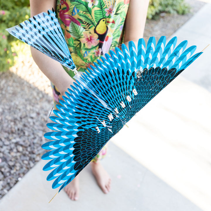 a white girl holds a blue rubberband flying bird above a sidewalk