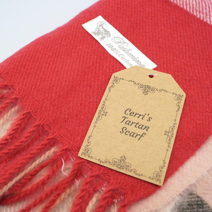 a red cashmere scarf with the label Cerri's Tartan Scarf on top of it