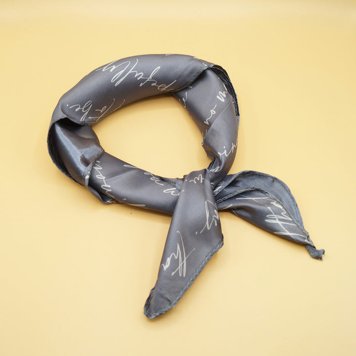 a gray scarf with white cursive words tied into a knot