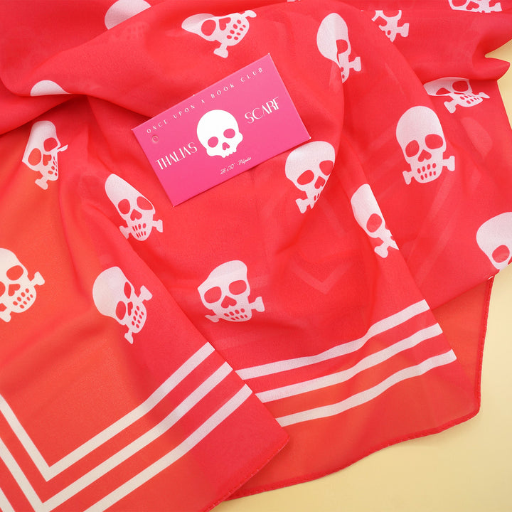 a hot pink scarf with white skulls on it