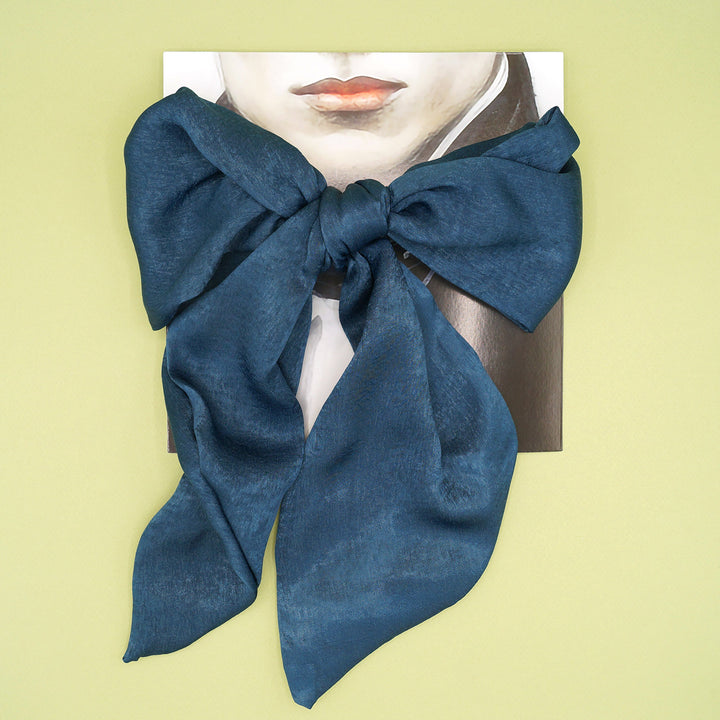 a dark blue skinny scarf tied in a bow around a card printed with a vintage looking vampire.