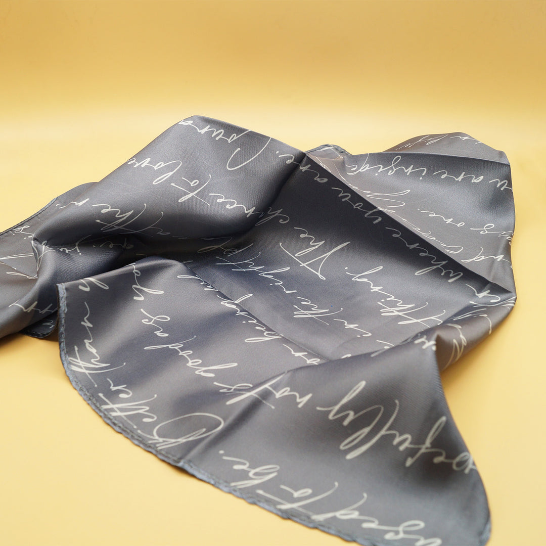 a gray scarf with white cursive words on it 