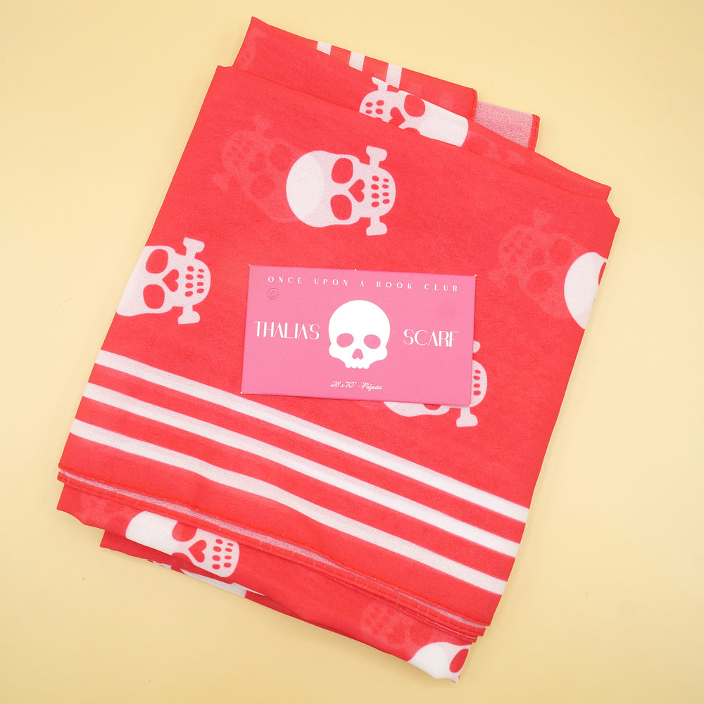 a hot pink scarf folded up into a square with white skulls on it