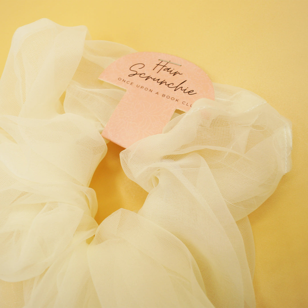 a white tulle scunchie on a yellow background