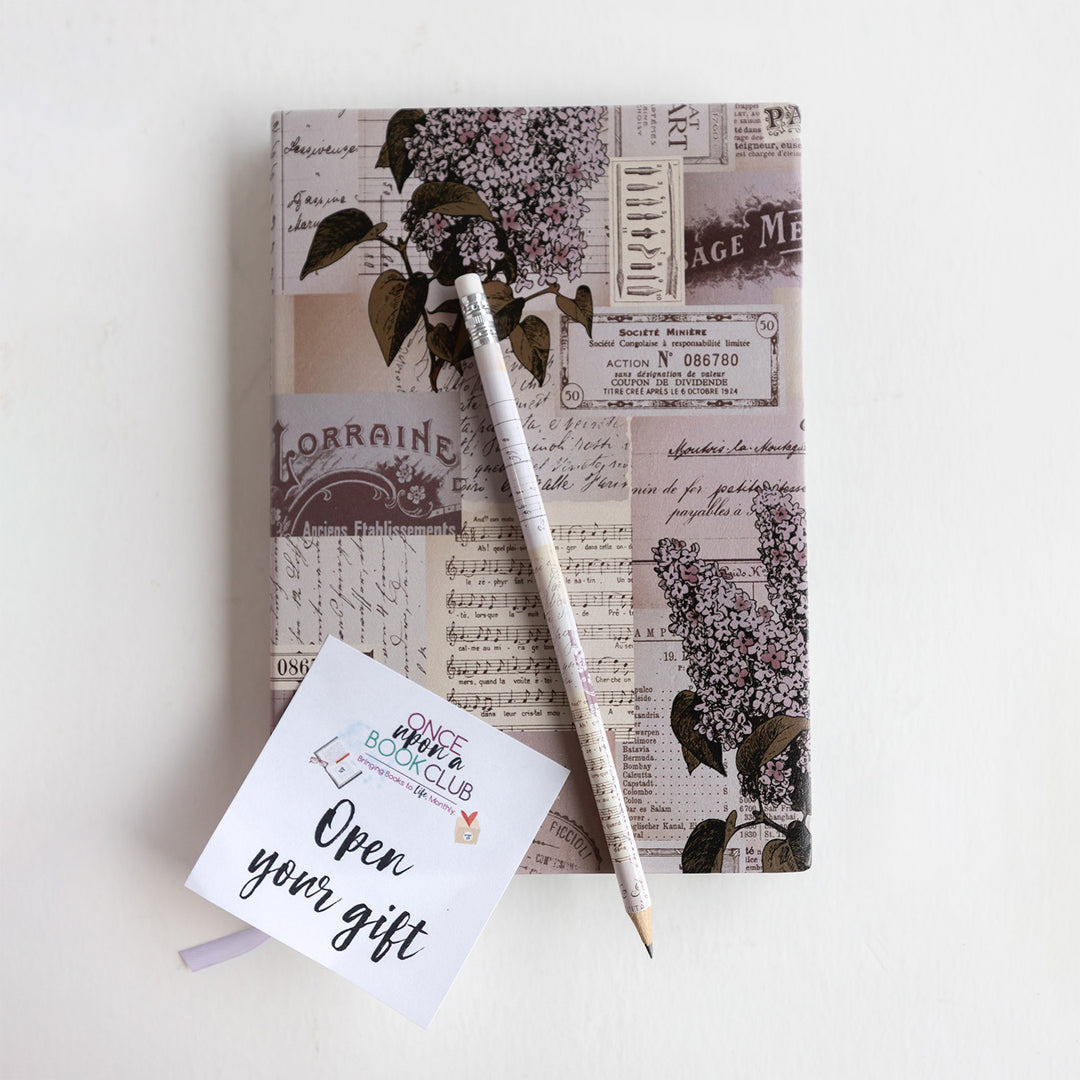A pencil and an open your gift sticky note lay on a journal. The journal has a patchwork design on it showing music notes, old clips from newspapers, flowers, etc.