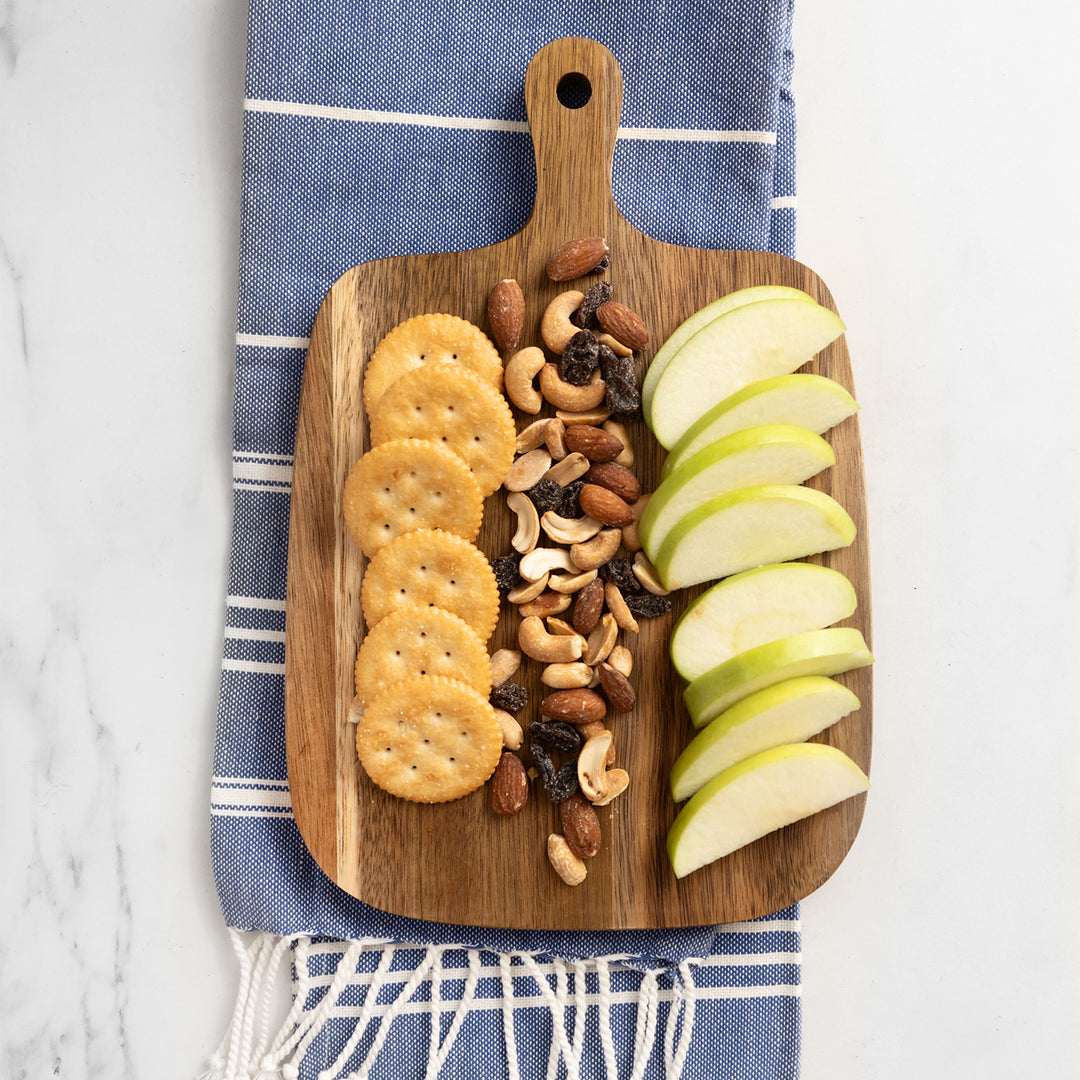 a wooden serving board with apple slices, nuts, and ritz crackers sits on a blue and white towel