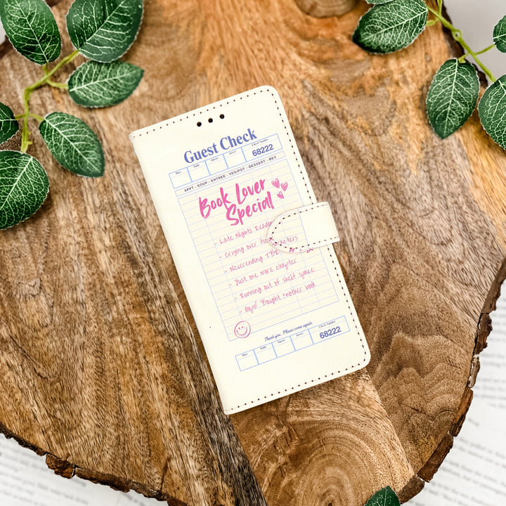 Phone case with a Book Lover Special restaurant check design and quirky list of what's included in pink writing.