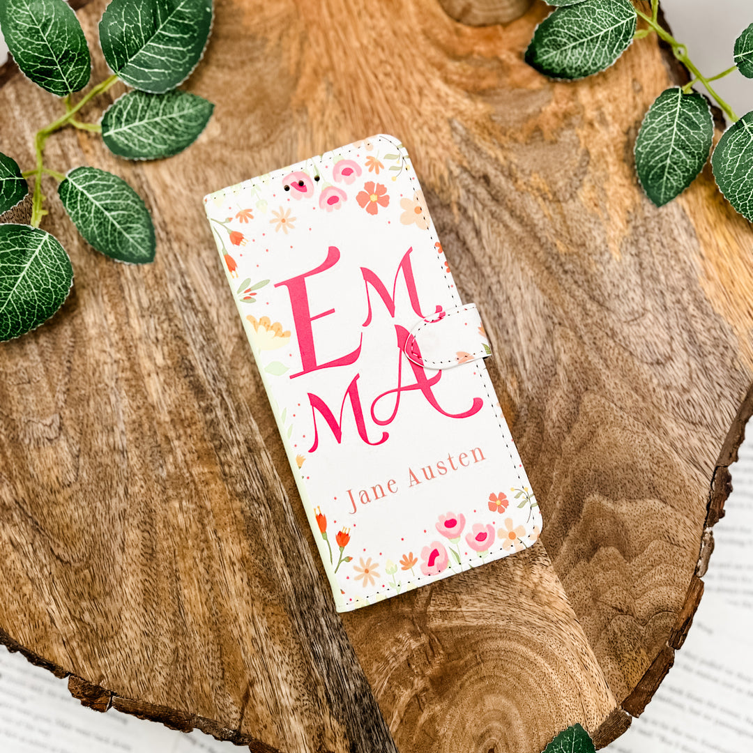 Phone case with 'Emma' by Jane Austen design on a wooden surface with leaves.