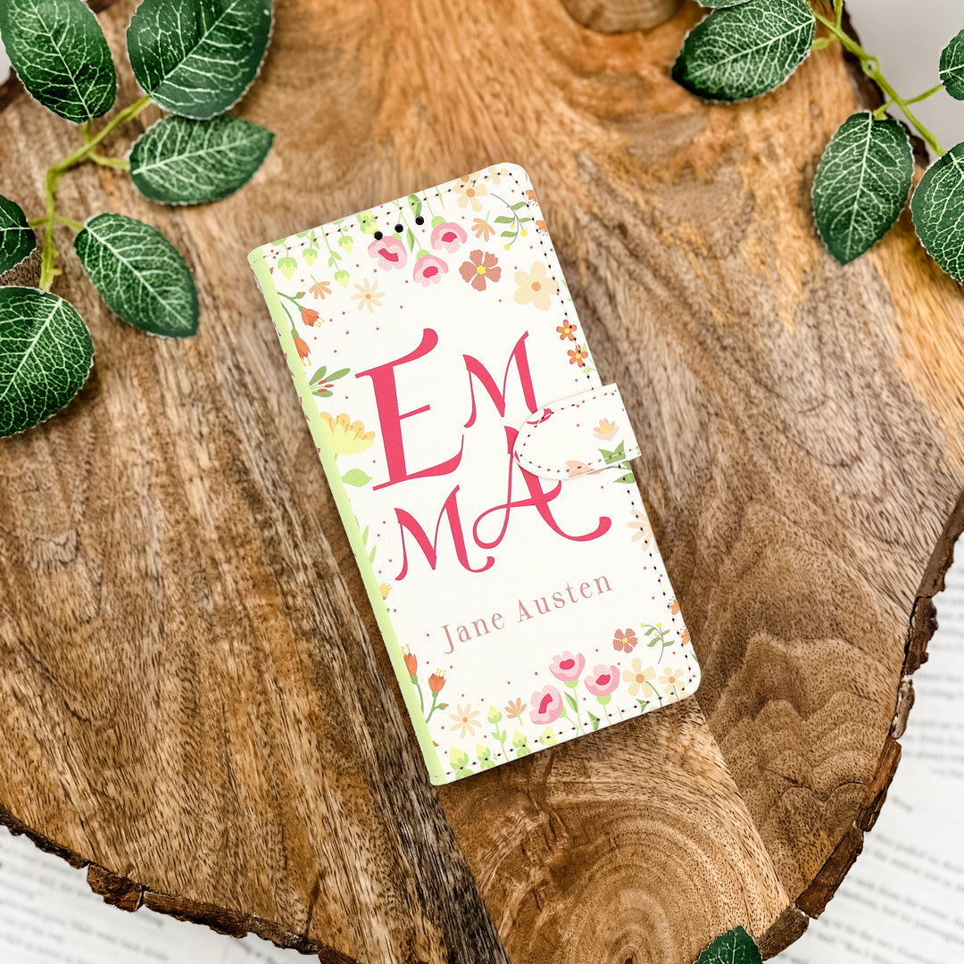 Phone case with 'Emma' by Jane Austen design on a wooden surface with leaves.