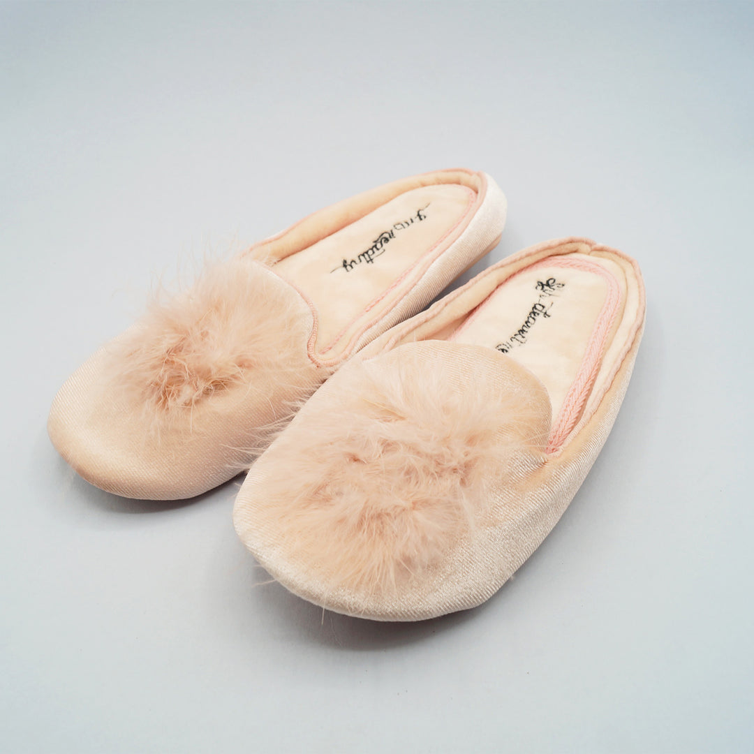 pale pink slip-on slippers with pompoms on the front. There is black writing embroidered on the inside bottoms of the slippers that says "Shh dearest readers...I'm reading..."