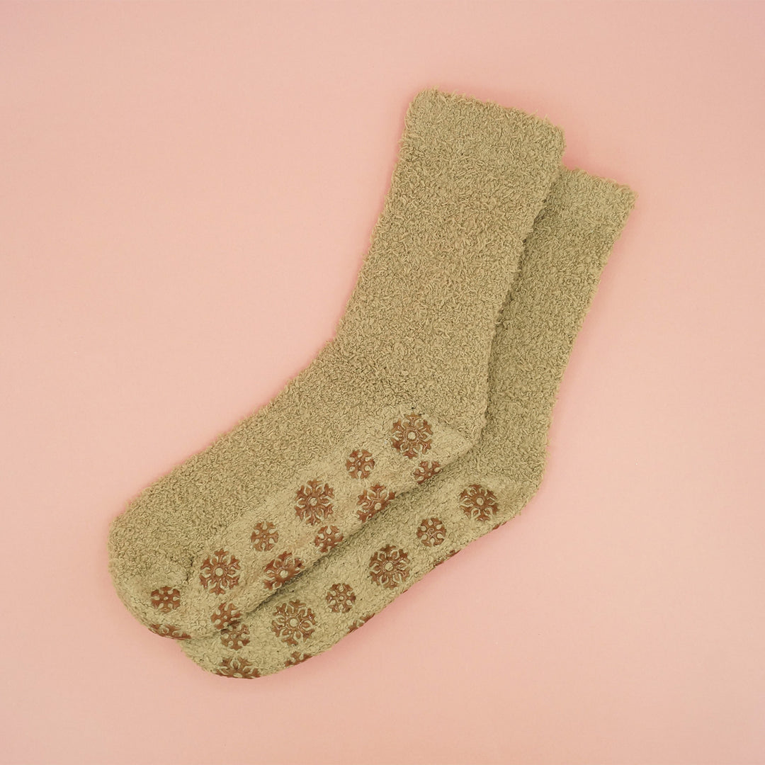 A pair of slipper socks with brown snowflake-shaped grips on the bottom