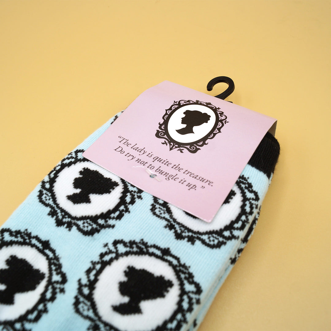 a pair of socks that are light blue and black with the pattern of a woman's silhouette sideways in the mirror