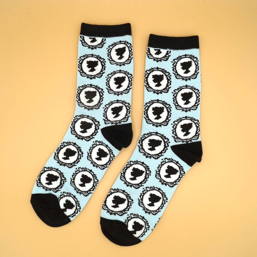 a pair of socks that are light blue and black with the pattern of a woman's silhouette sideways in the mirror