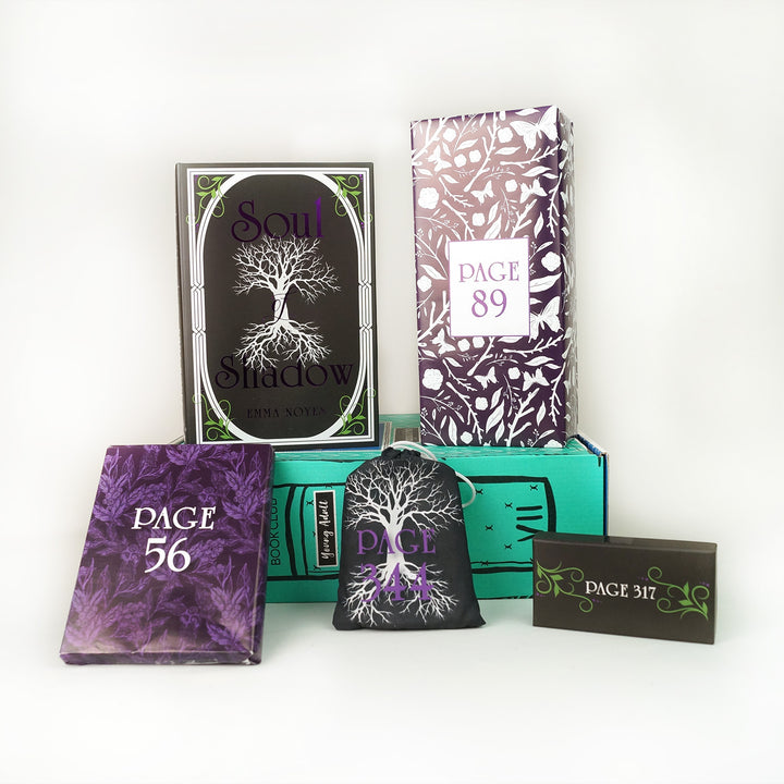 A hardcover copy of Soul of Shadow by Emma Noyes surrounded by wrapped gifts labeled with page numbers and paper items.