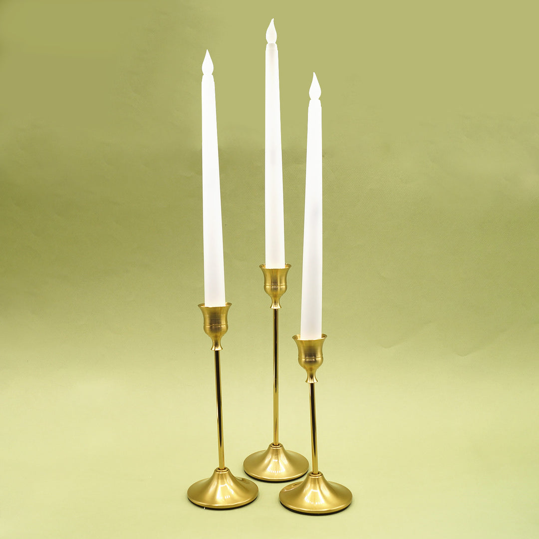 A set of three gold candle holders with a white faux candle in each.