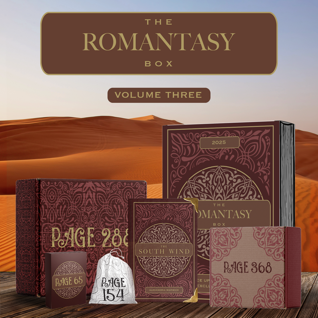 The Romantasy Box Volume 3 featuring The South Wind by Alexandria Warwick featuring red and gold details. Surrounding by red and gold packaging. All components stand in front of a desert background.