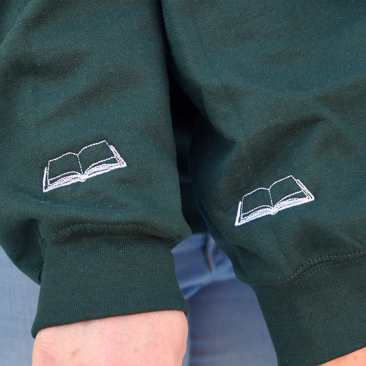 Green sweatshirt with white embroidered book design on sleeves