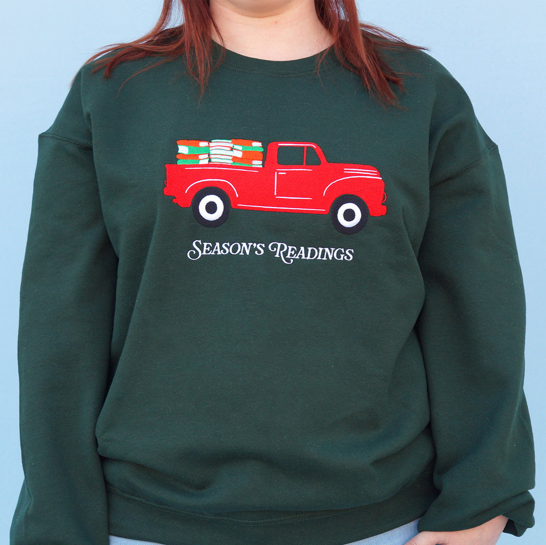 Green sweatshirt with a red truck and 'Season's Readings' text design on a blue background