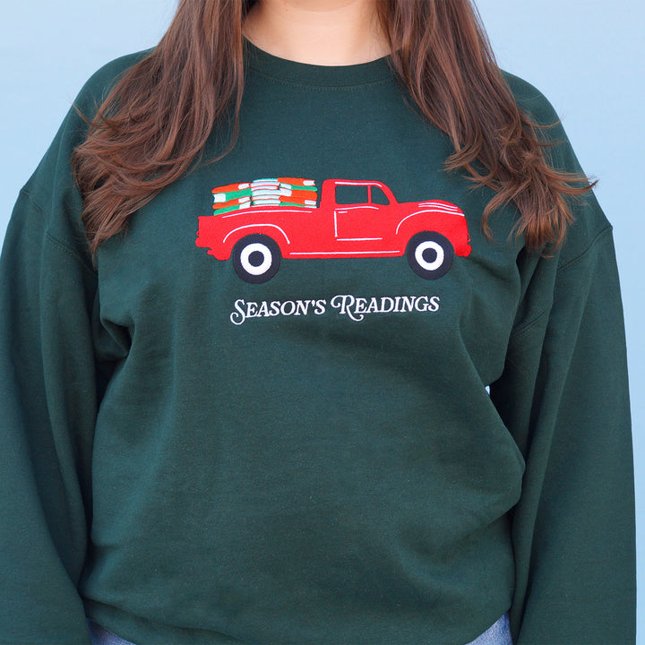 Green sweatshirt with a red truck and 'Season's Readings' text design on a blue background