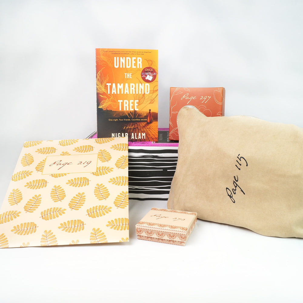 a paperback edition of Under the Tamarind Tree and a square box sit on a pink box. In front of the pink box are a folder, square box, and tan fabric bag. The boxes and bags all have page numbers.