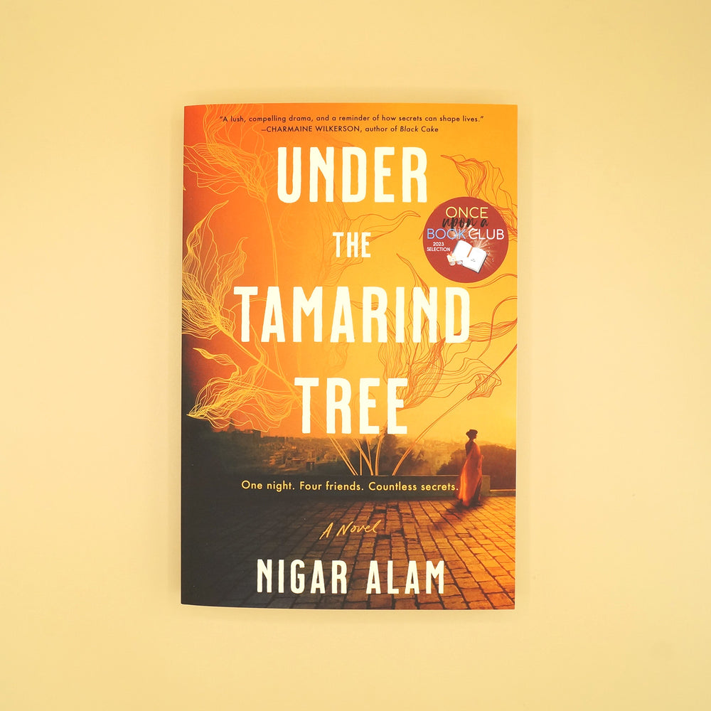 a paperback copy of "Under the Tamarind Tree" by Nigar Alam sits on a light yellow background