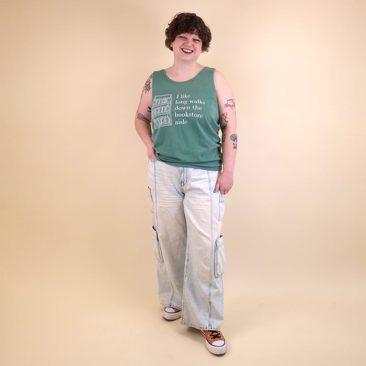 Woman wearing a green tank top with text that reads 'I like long walks down the bookstore aisle' and bookshelf graphic on a beige background.