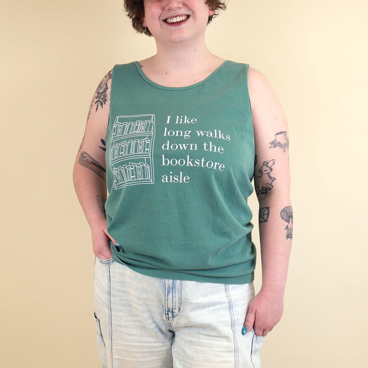 Woman wearing a green tank top with text  that reads 'I like long walks down the bookstore aisle' and bookshelf graphic on a beige background
