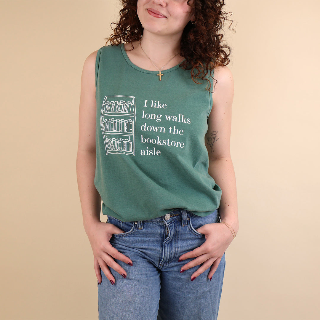 Woman wearing a green tank top with text that reads 'I like long walks down the bookstore aisle' and bookshelf graphic on a beige background.
